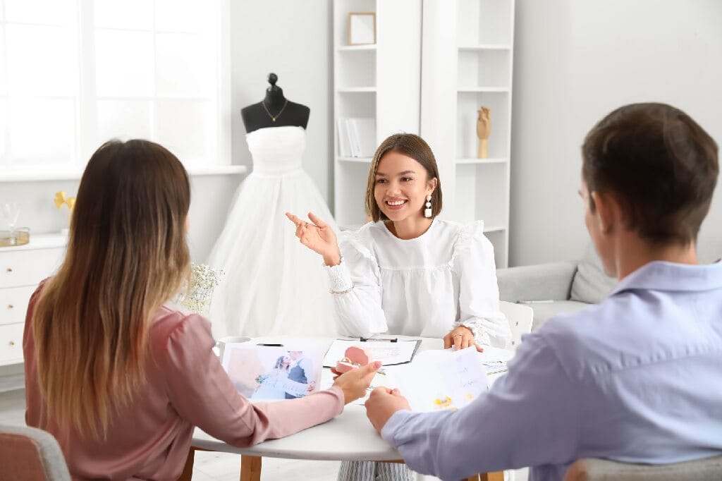 Female,Wedding,Planner,Discussing,Ceremony,With,Clients,In,Office